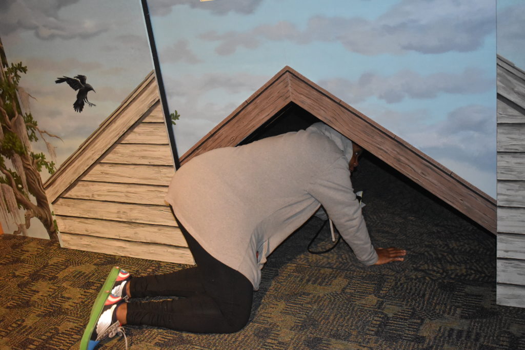 Brown girl checking out crawl space used for underground railroad in Rochester