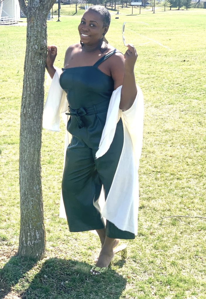 Brown girl outside in the park wearing green jumpsuit with yellow shoes.