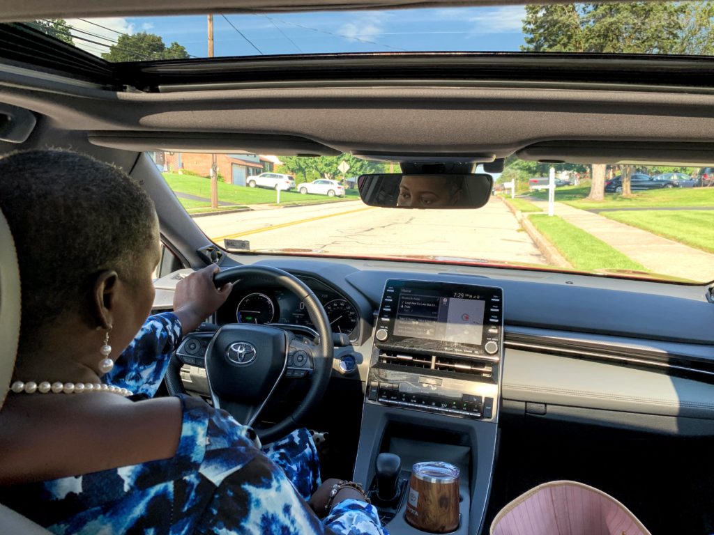 Brown girl doing safety checks before road trip in hybrid Toyota Avalon 2020